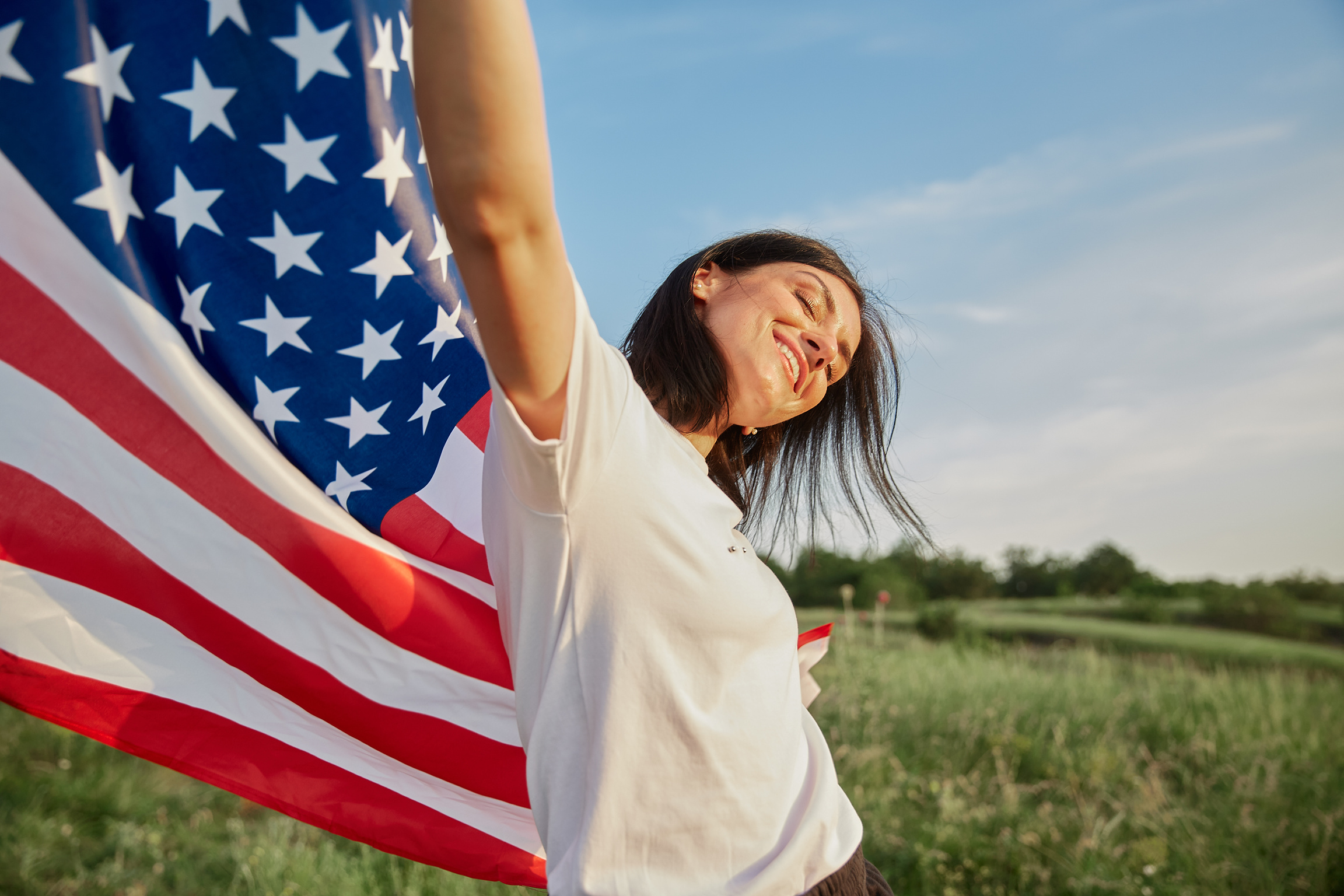 4 july. Woman with American flag on sunset landscape